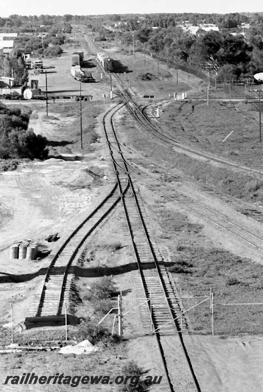 P23975
Sidings,  diesel hauled train approaching in distance, road crossings, tracks, gate, Webberton, GA line, elevated view
