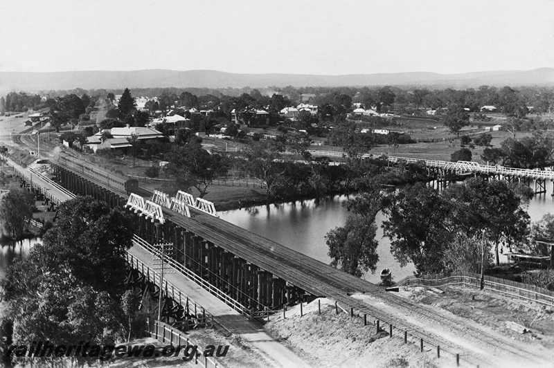 P23980
The three bridges over the Swan River at Guildford. On the left is the old railway bridge built in 1880 and converted to road traffic, next is the 1897 railway bridge with a train headed for Guildford, right is the first road bridge, elevated overall view looking east. ER line
