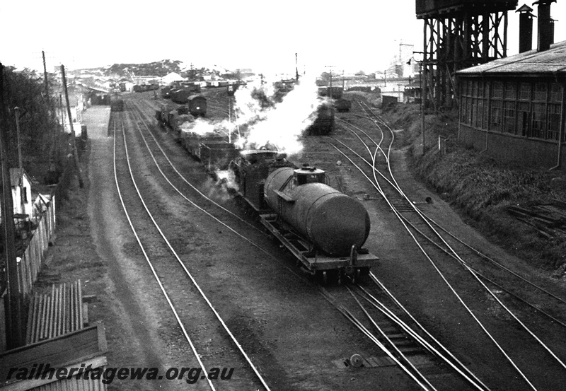 P24036
G class 233, shunting wagons including tanker, station building, platform, yard, back fences, various wagons in sidings, water tower, part of roundhouse, Bunbury, SWR line, side and end view from elevated position
