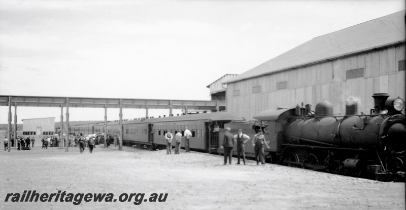 P24084
L class loco, rake of platform ended carriages, large mine structures, passenges scattered on the platform, opening of the Big Bell railway and mine
