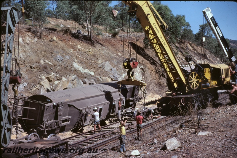 T05086
Cowans Sheldon 60 ton crane No. 31, lifting derailed and lying on its side  WWA class 32336 standard gauge grain hopper, Brambles Kato crane standing by, workers, Jumperkine, Avon Valley line
