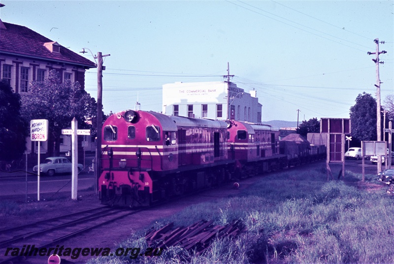 T05440
Midland Railway Co (MRWA) G class 50 and another diesel double heading a goods train from Walkaway, crossing road to enter MRWA yard, The Commercial Bank building, rail crossing sign, Midland Junction, MR line ,front and side view
