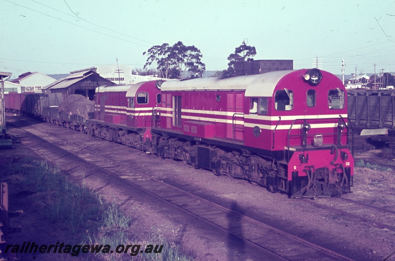 T05442
Midland Railway Co (MRWA) G class 50 and  F class diesel, double heading goods train, bracket signals, sheds, arriving from Walkaway at Midland Junction, MR line, side and front view, water bag hanging frim the end handrail, cast iron water tank in the background
