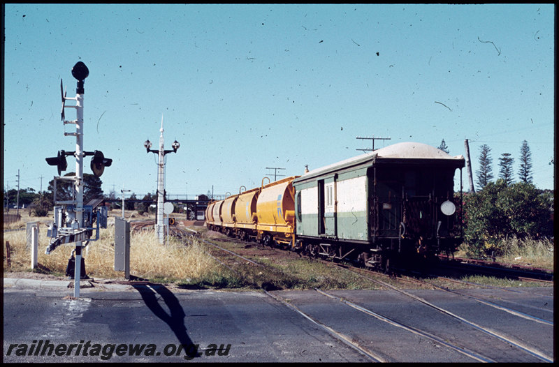 T07591
Z Class 9 brakevan, XW Class grain wagons, rear of Down goods train, RA Class 1910 on head end, Cottesloe, Jarrad Street level crossing, boomgate, shunt dollies, footbridge, ER line
